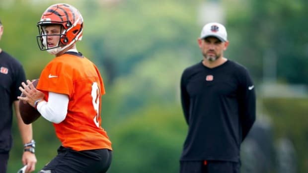 Cincinnati Bengals quarterback Joe Burrow (9) drops back to throw as Cincinnati Bengals head coach Zac Taylor, left, and quarterbacks coach Dan Pitcher observe, Monday, Aug. 16, 2021, at the practice fields next to Paul Brown Stadium in Cincinnati.  